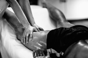 Sports massage - Leg massage - Physical therapist doing massage of legs, applying strong finger pressure. Black and white photo, selective focus.